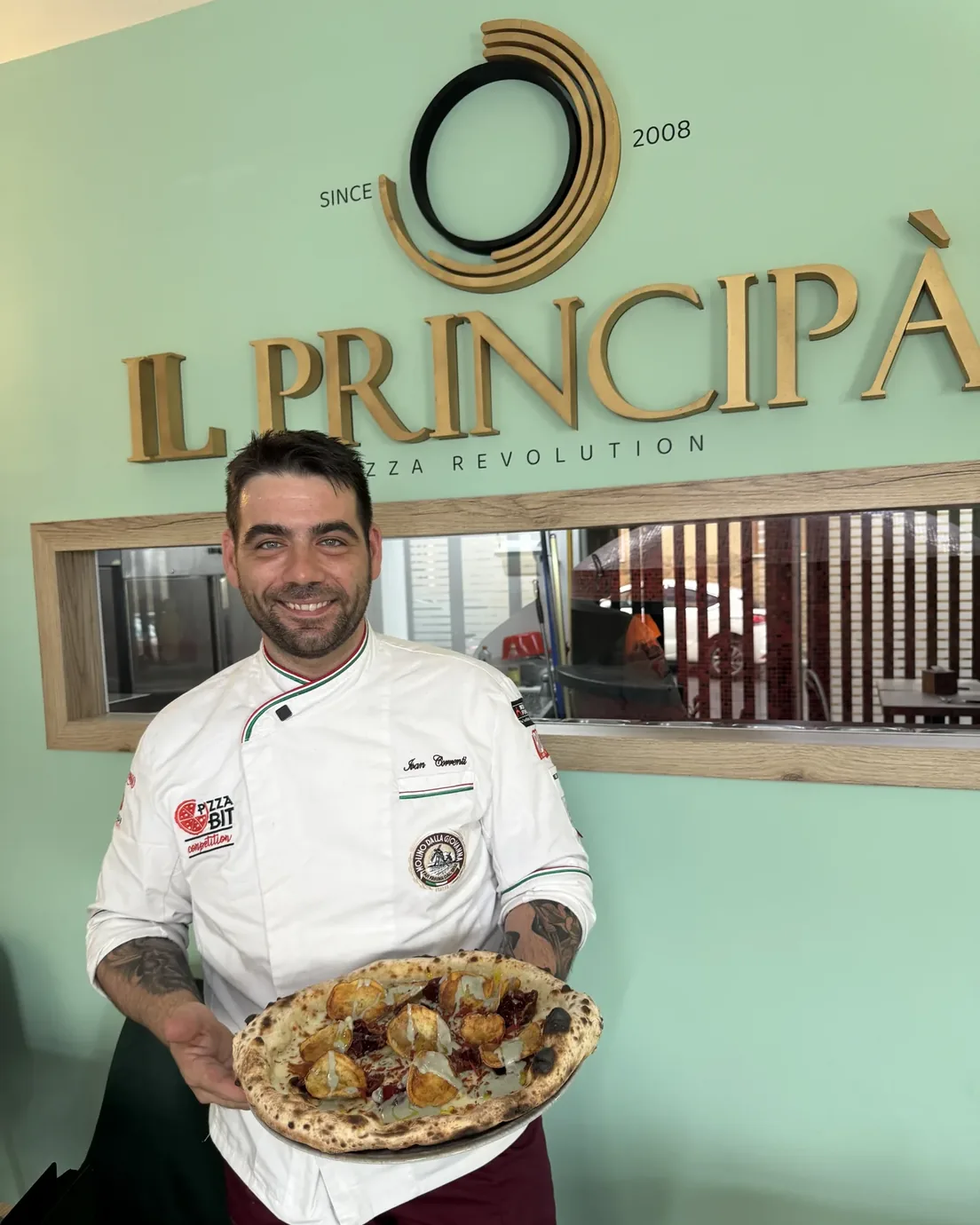 Ivan Correnti con una pizza, sotto l'insegna del Principà